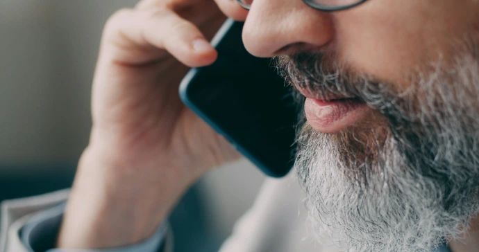A man with a beard talking on a cell phone